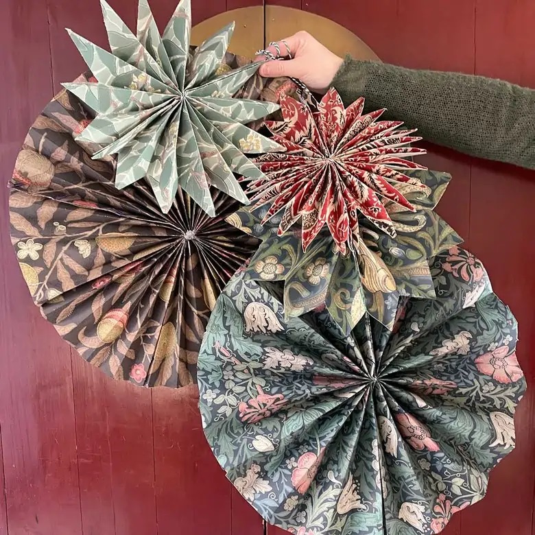 How To Plan A Christmas Party - make your own party decorations like these paper fans from The Listed Home.